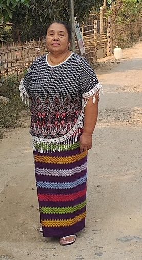 Daw Nang Nwe stands on dirt road outside her shop