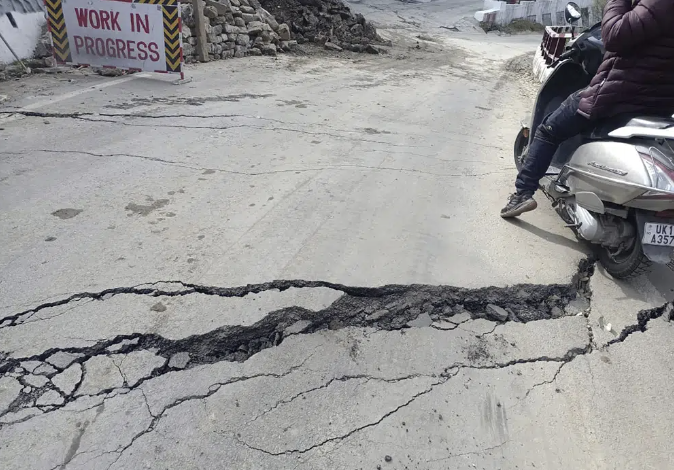 A motorist navigates his way through a crack on a road in Joshimath, India