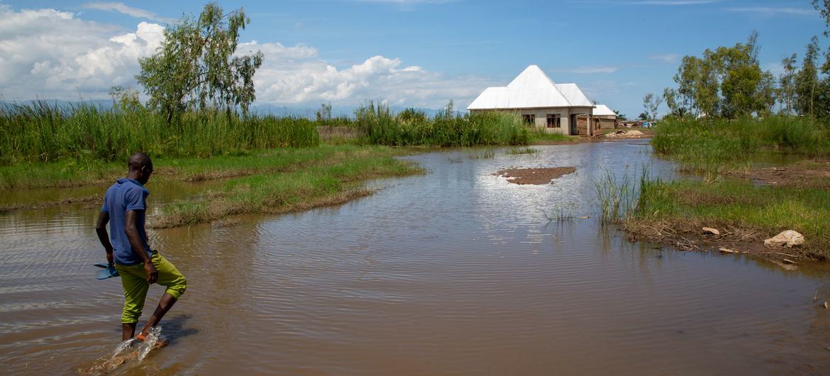 © UNICEF/Karel Prinsloo Un homme marche dans les eaux de crue à Gatumba, au Burundi, une région qui reçoit des précipitations imprévisibles en raison du changement climatique.