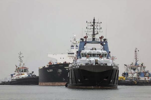 Tugboats pull a ship in the Suez Canal between the cities of Port Said and Ismailiya, Egypt