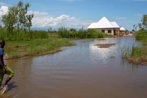 © UNICEF/Karel Prinsloo Un homme marche dans les eaux de crue à Gatumba, au Burundi, une région qui reçoit des précipitations imprévisibles en raison du changement climatique.